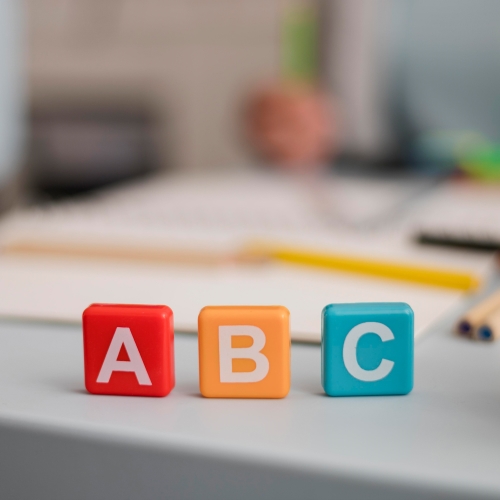 A close up of a block spelling abc and a pencil.